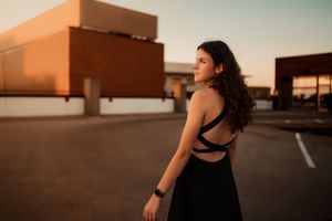 Person in black athletic wear poses in empty parking lot at golden hour.