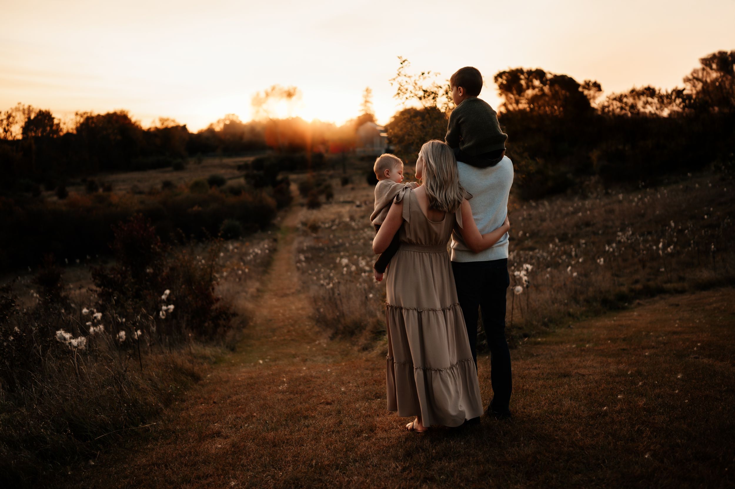 Silhouettes of a family walking together on a dirt path at sunset with dramatic golden light.