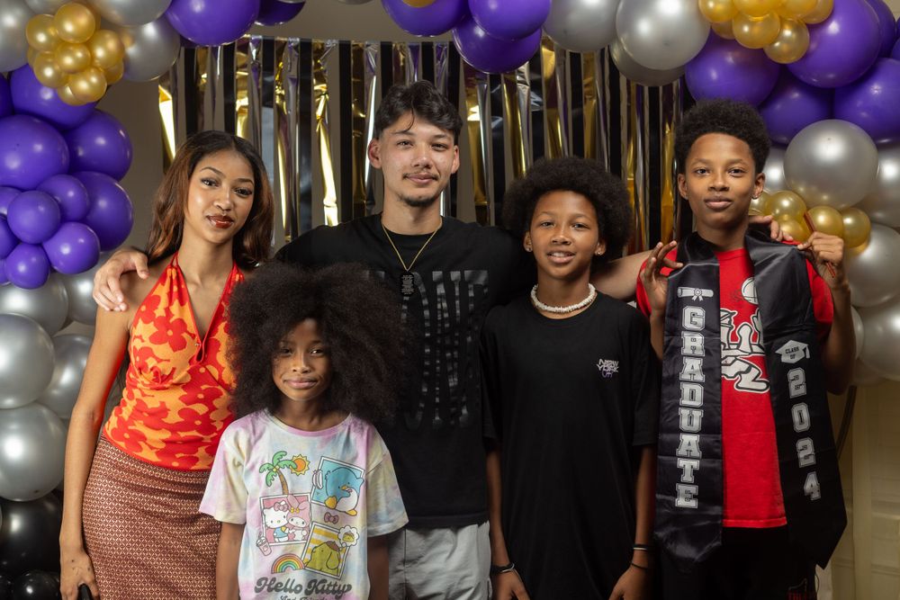 Group photo against backdrop with purple and gold balloons.