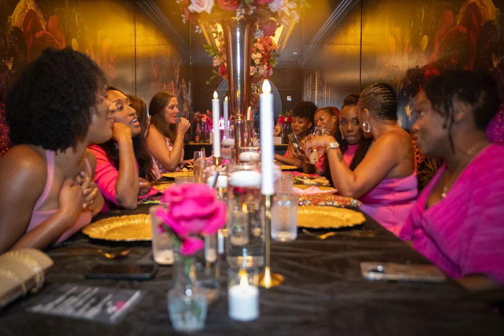 Festive dinner party with bright pink decor and table settings in warm lighting.