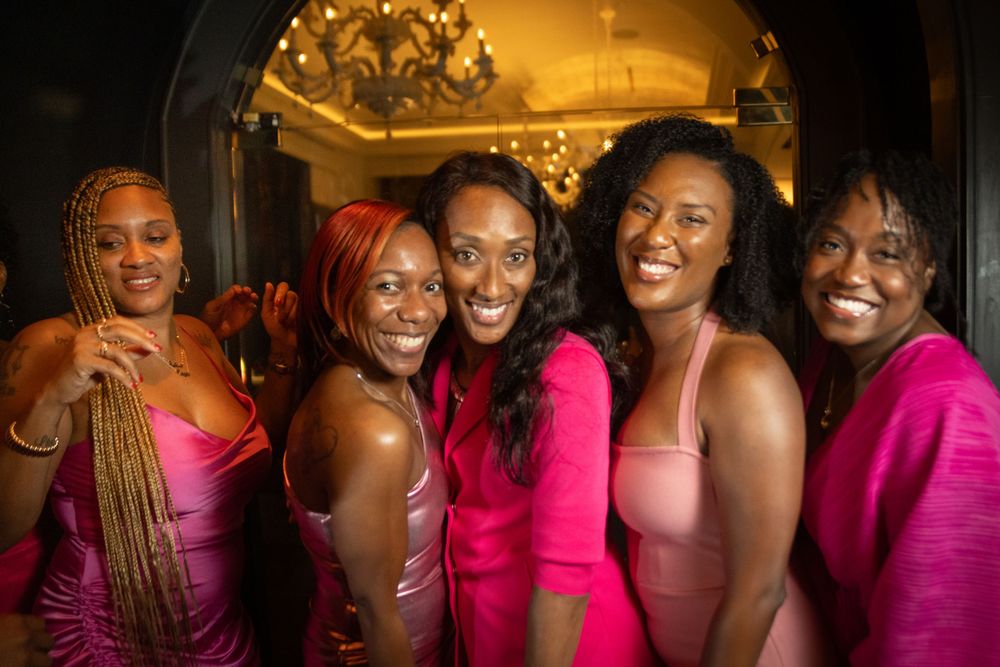Group wearing vibrant pink outfits posing together at an elegant evening event.