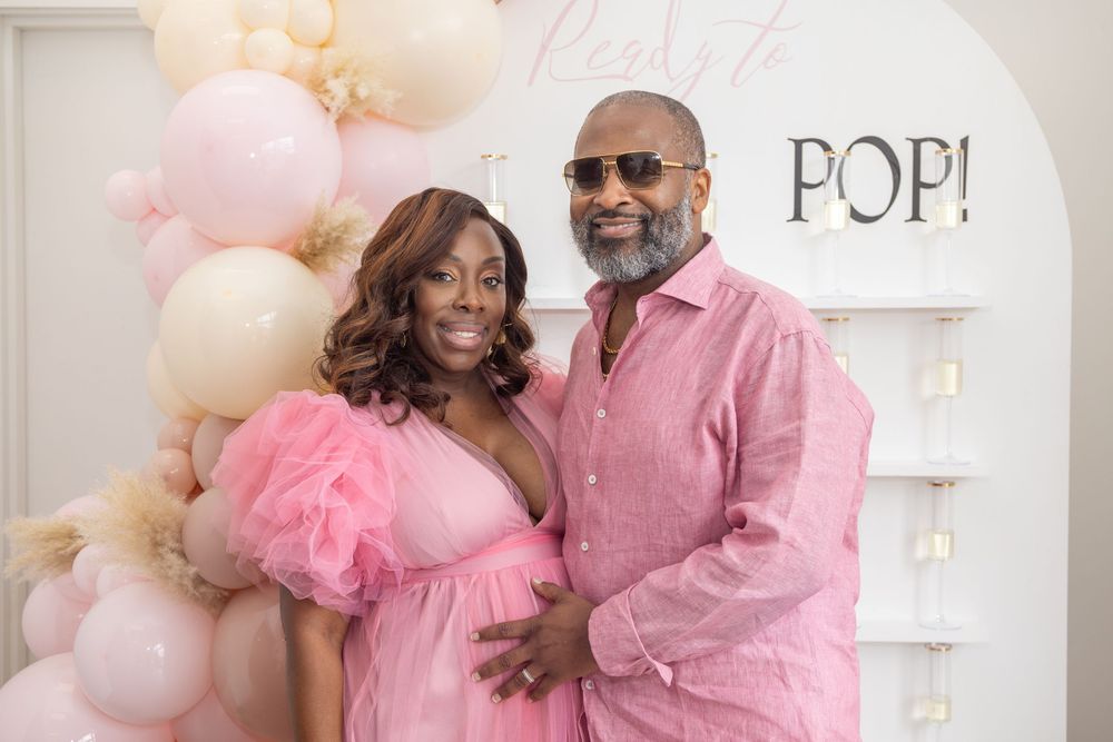 Festive party setup with pink and cream balloon garland and 'POP!' text display on white wall.