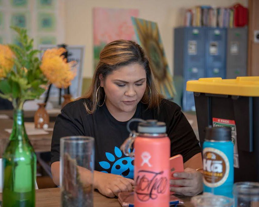 Person in black t-shirt with drinks at a casual dining table.