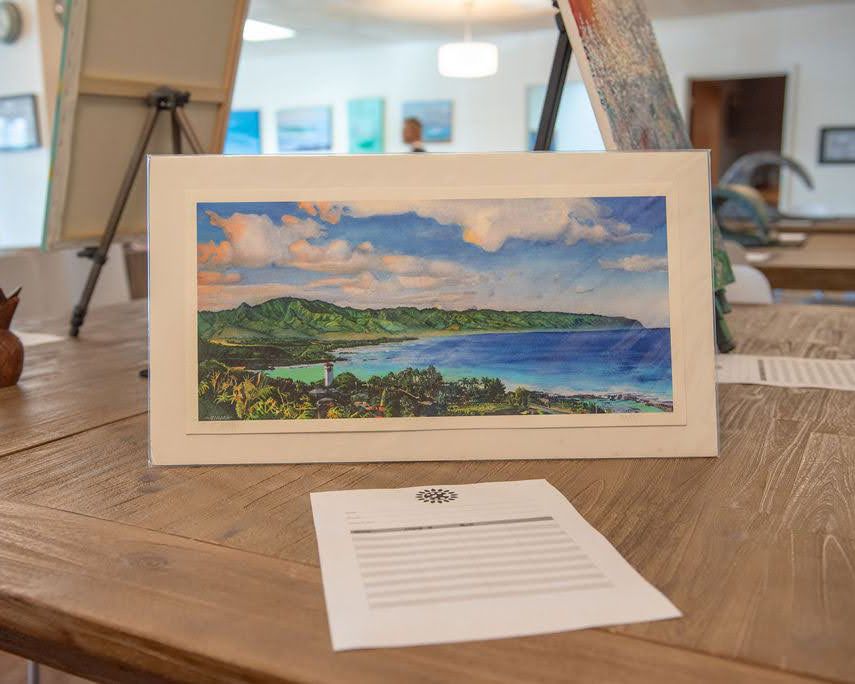 A framed coastal landscape photograph displayed on a wooden table with accompanying documentation.