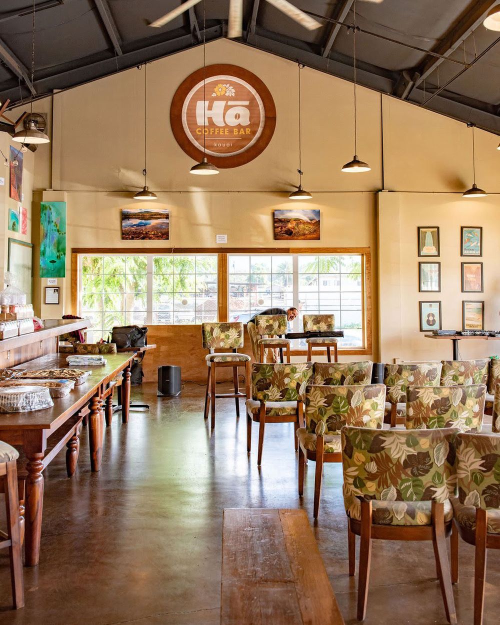 Modern cafe interior with KG logo, floral upholstered chairs, and high vaulted ceilings.