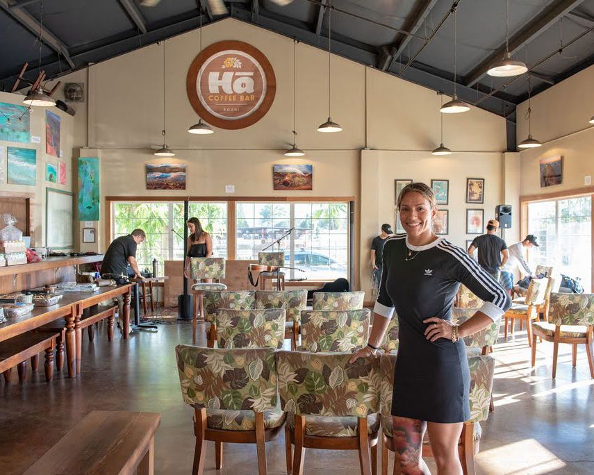 Interior of a modern coffee shop with floral upholstered chairs and rustic decor.
