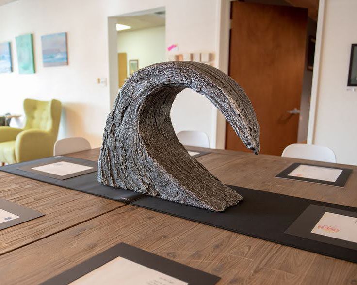 A decorative wave-shaped sculpture made of driftwood on a wooden conference table.