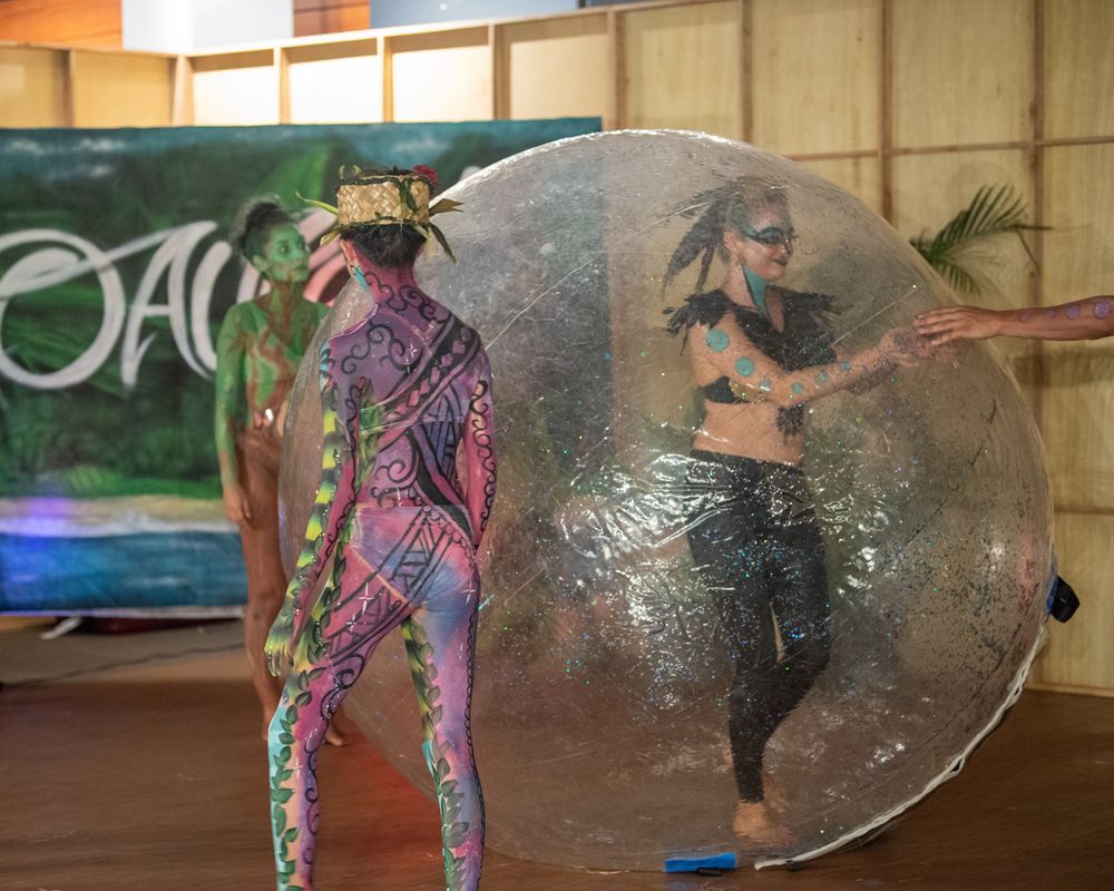 Two performers dancing with a large bubble or sphere prop on stage.