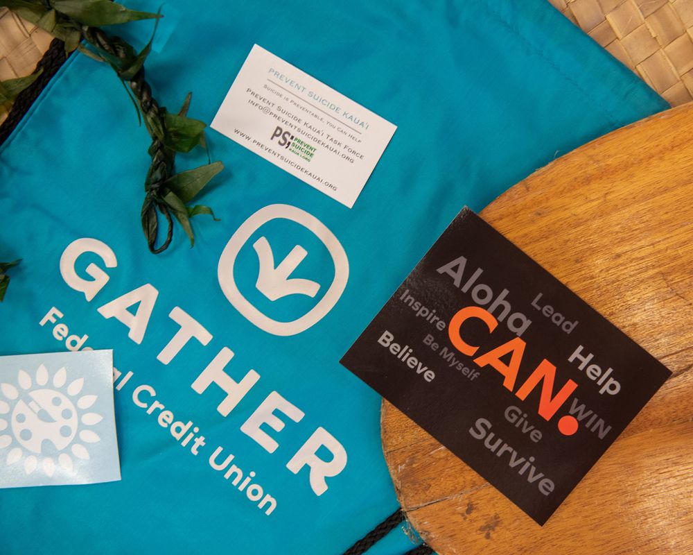 A blue Gather tote bag and promotional materials displayed on a wooden surface.