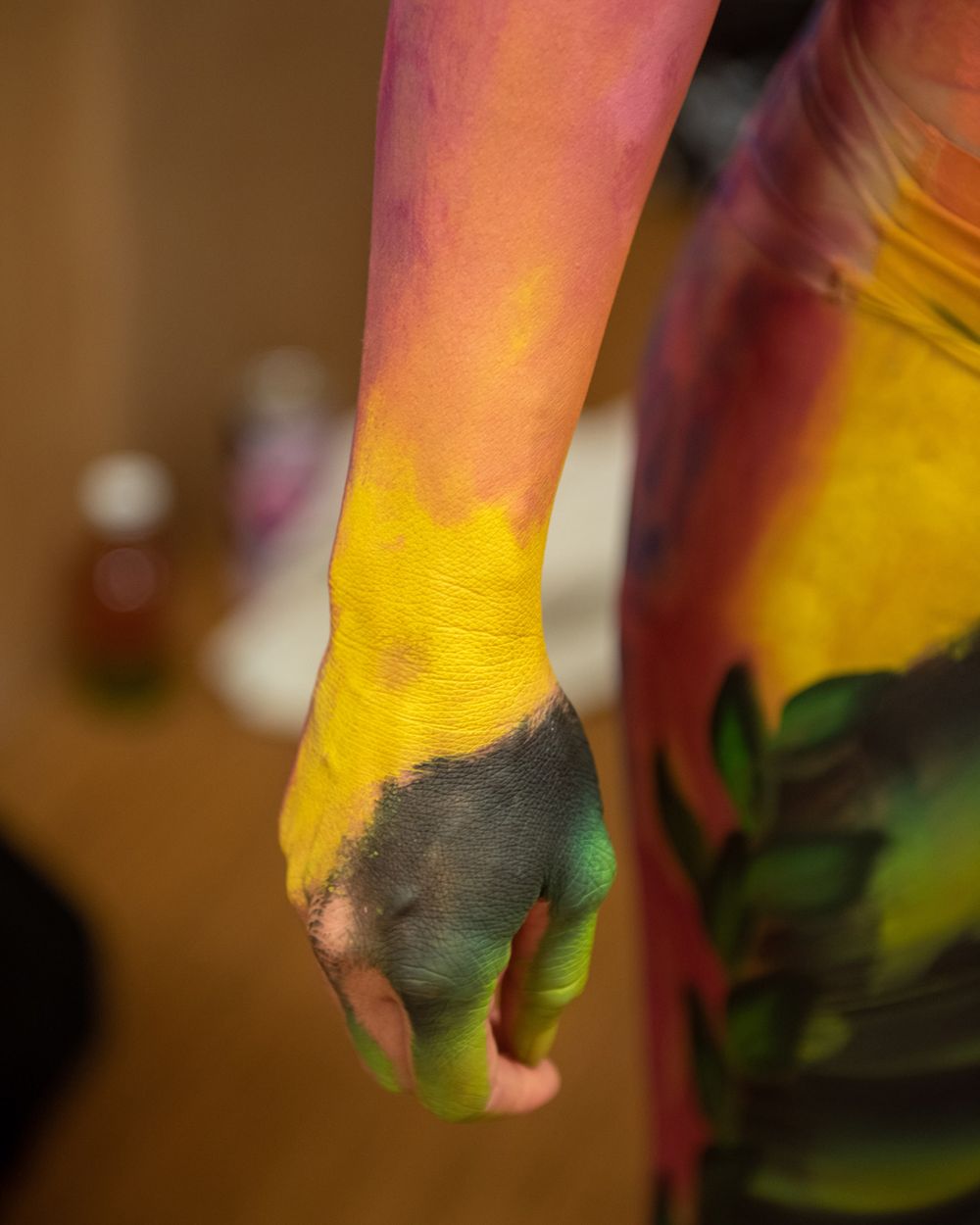 Close-up of an arm painted in vibrant yellow, pink, and black colors.