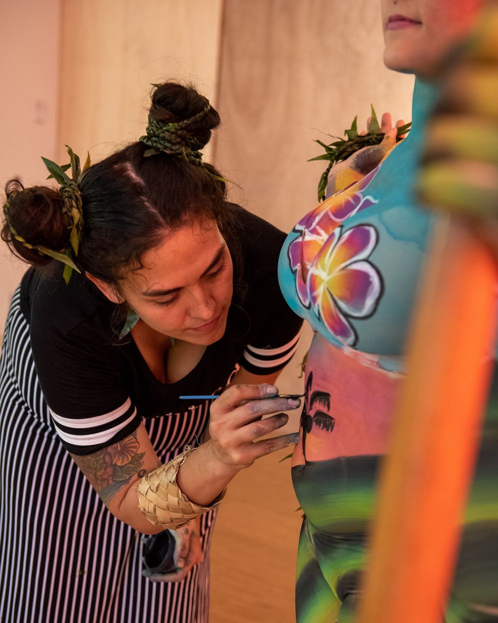 An artist with space buns hairstyle carefully painting a colorful design.