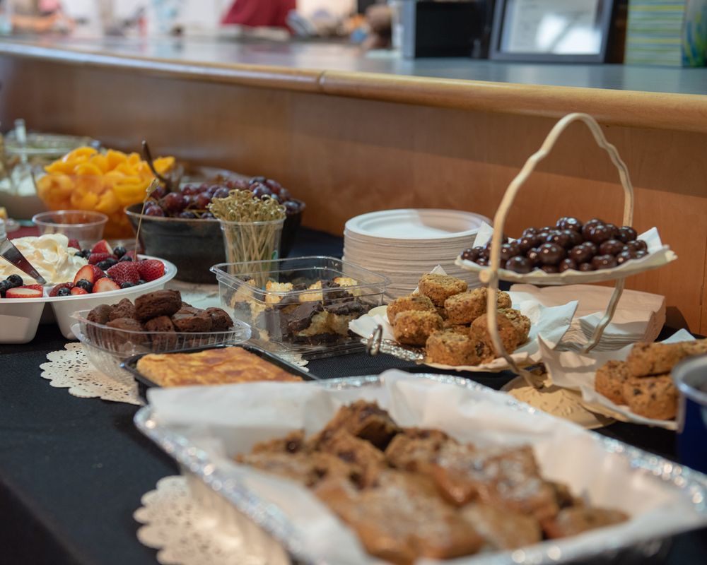 A buffet table filled with pastries, desserts and appetizers on decorative doilies.
