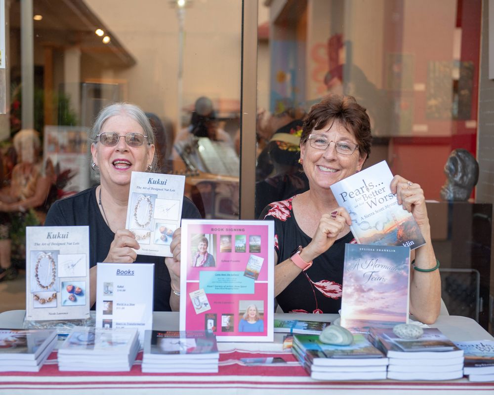 Authors display their published books at a signing table.