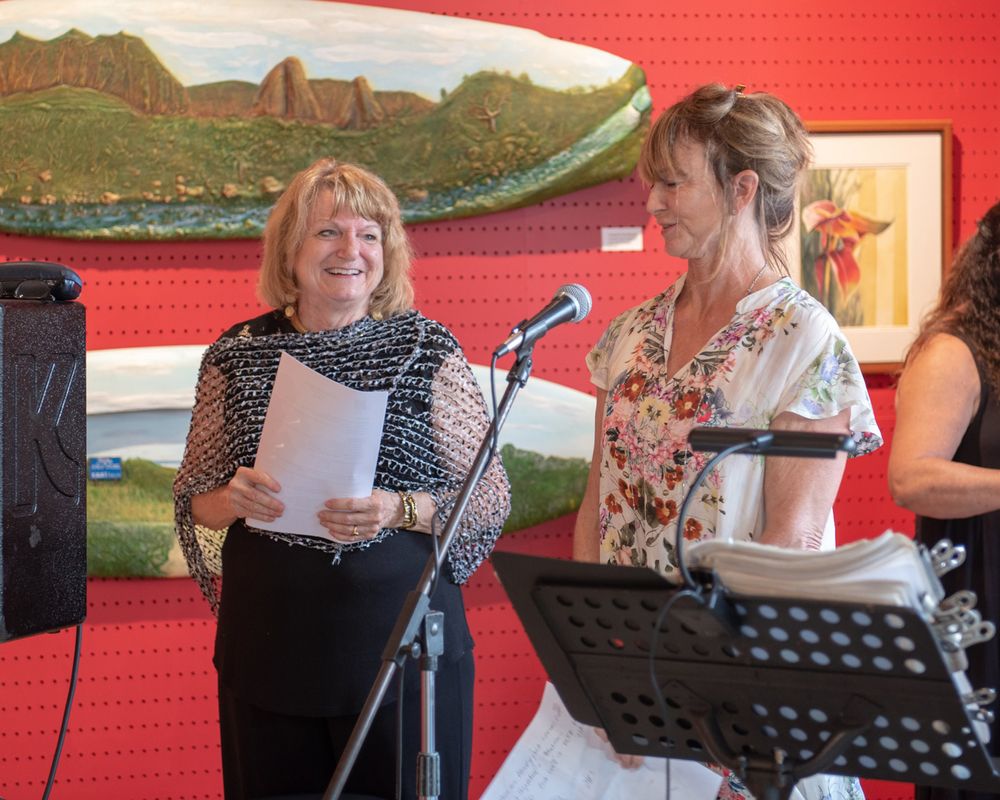 Performers read from scripts at microphones during an artistic presentation.