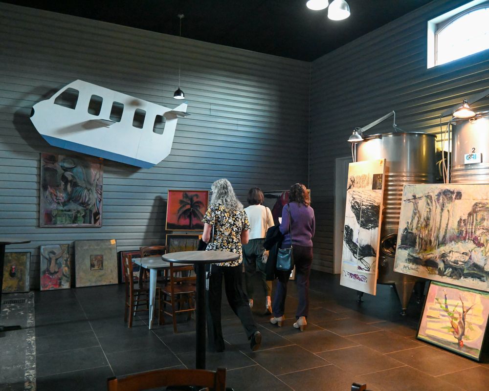 Gallery space with airplane sculpture mounted on wall and artwork displays.