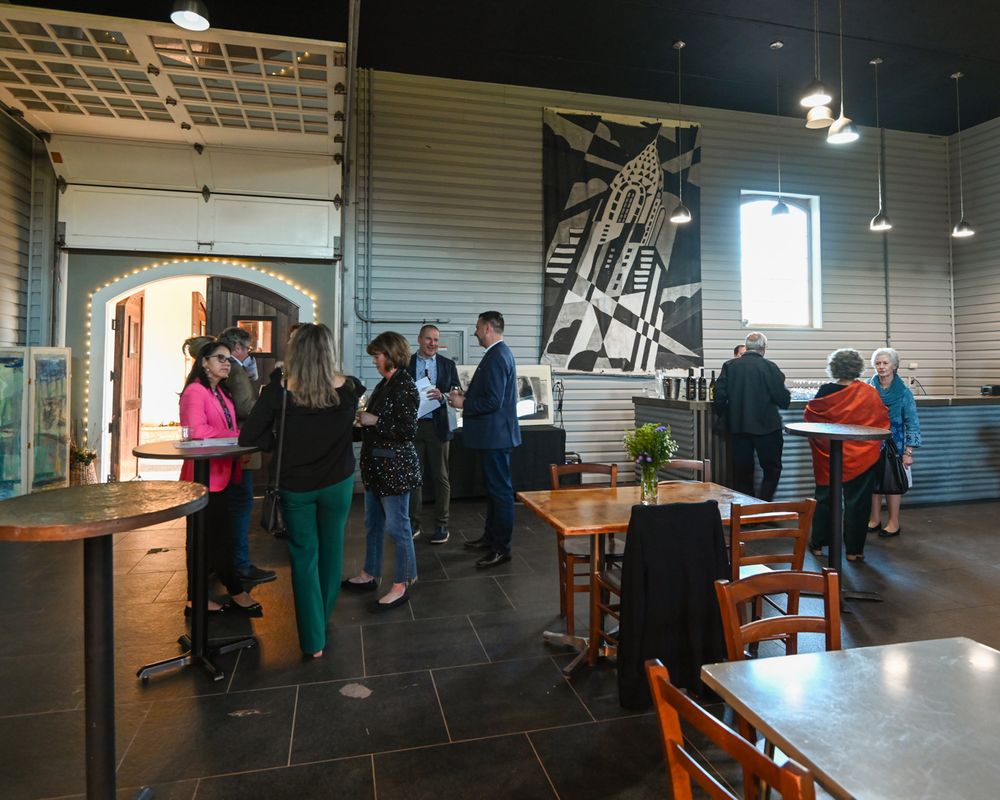 People gathered in modern cafe space with industrial decor and wall art.