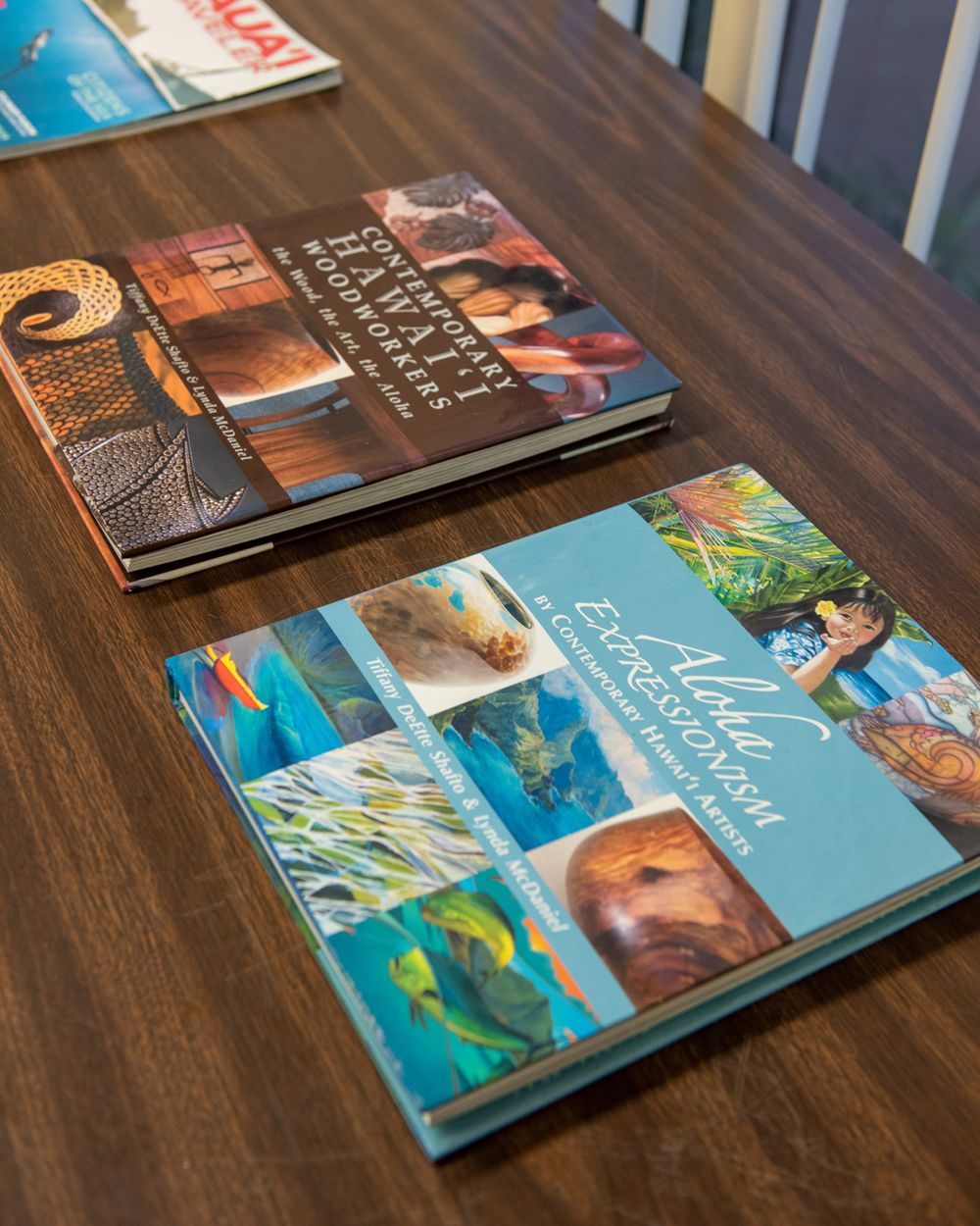 Art books displayed on dark wooden table surface.