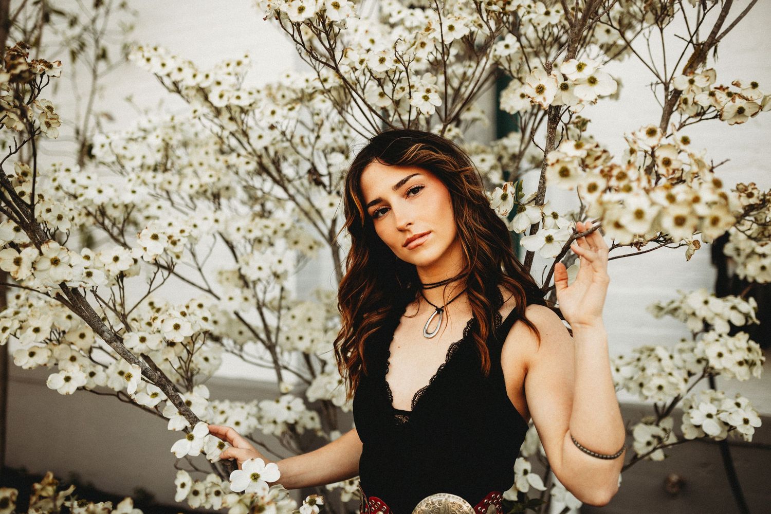 Senior girl standing in front of a tree with white spring blooms