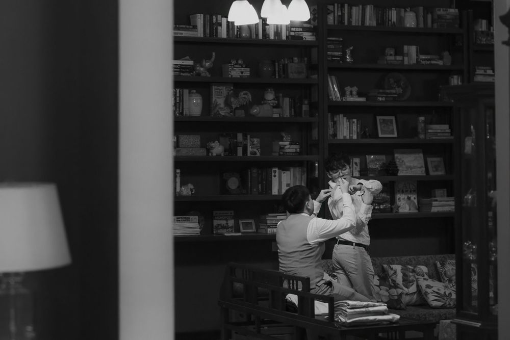 A romantic black and white scene of a couple embracing in a bookstore with shelves of books behind them.