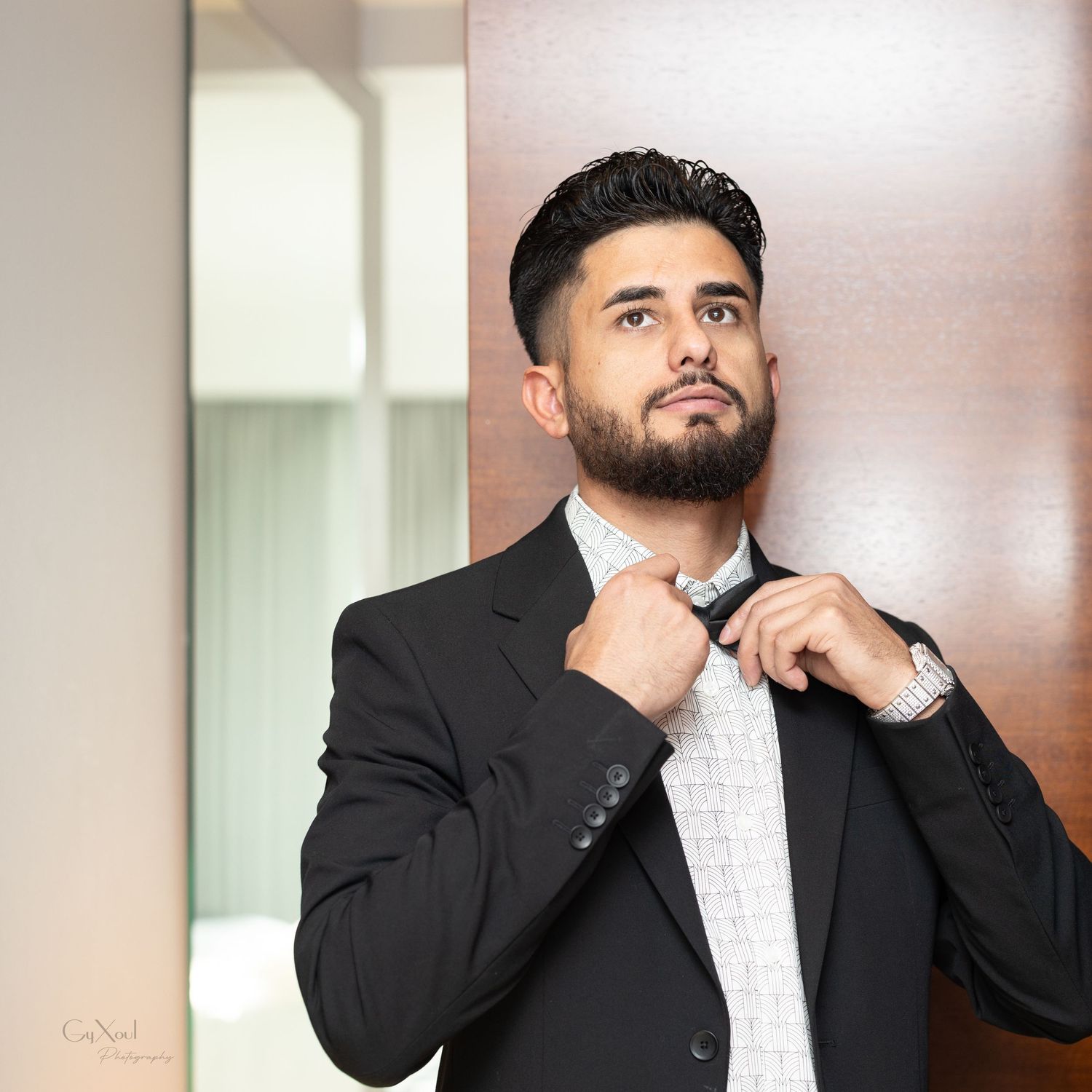 Formal portrait of person adjusting black tie and white collar.