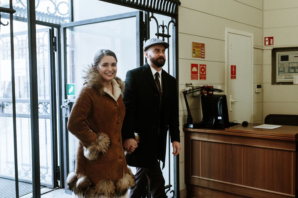 A couple walking through a building entrance wearing winter coats.