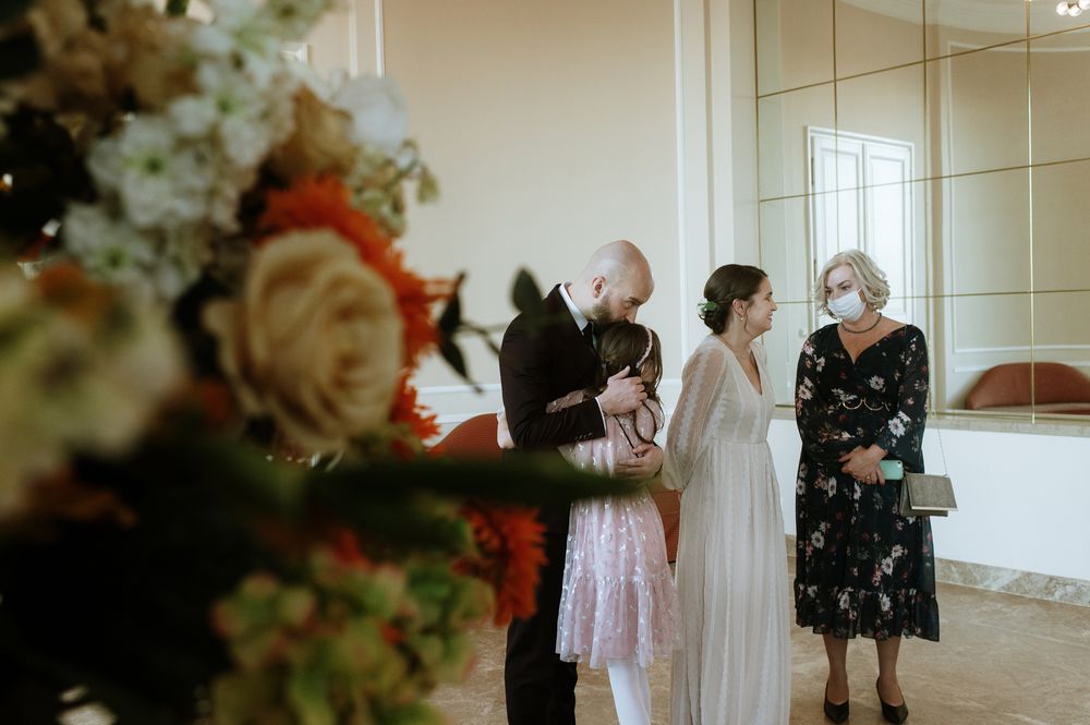 Small group gathered in an elegant room with floral arrangements during a wedding celebration.