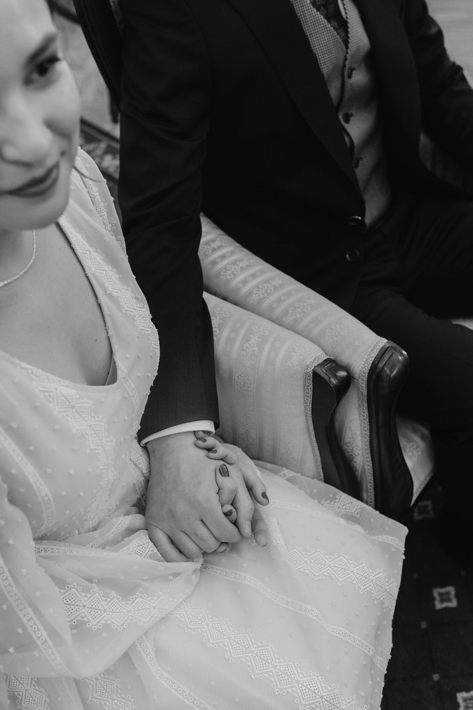 Black and white image showing hands adjusting a white lace wedding dress in a series of detail shots.
