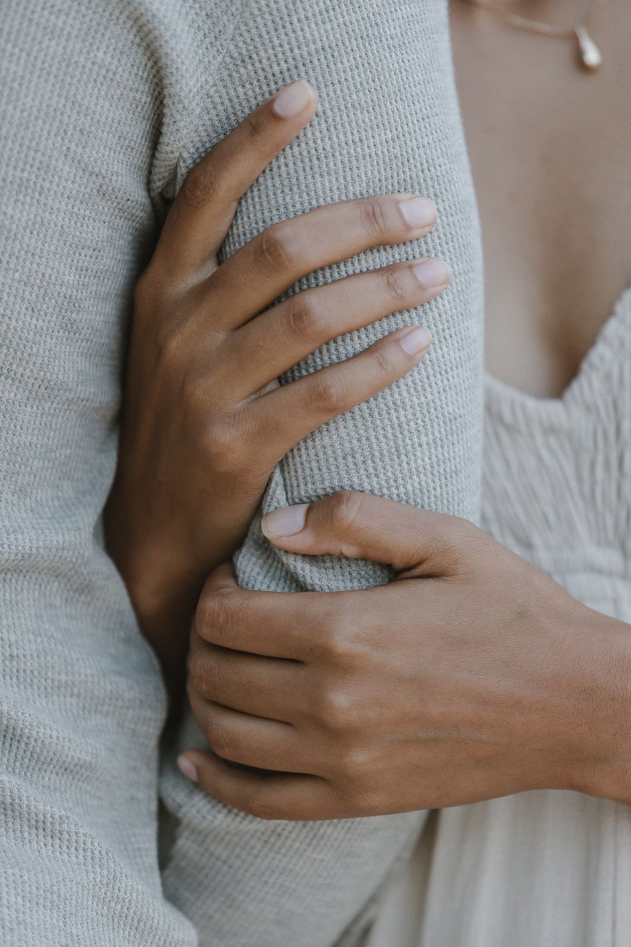 Close-up of hands gently holding a soft gray sweater showing tender intimacy and comfort.