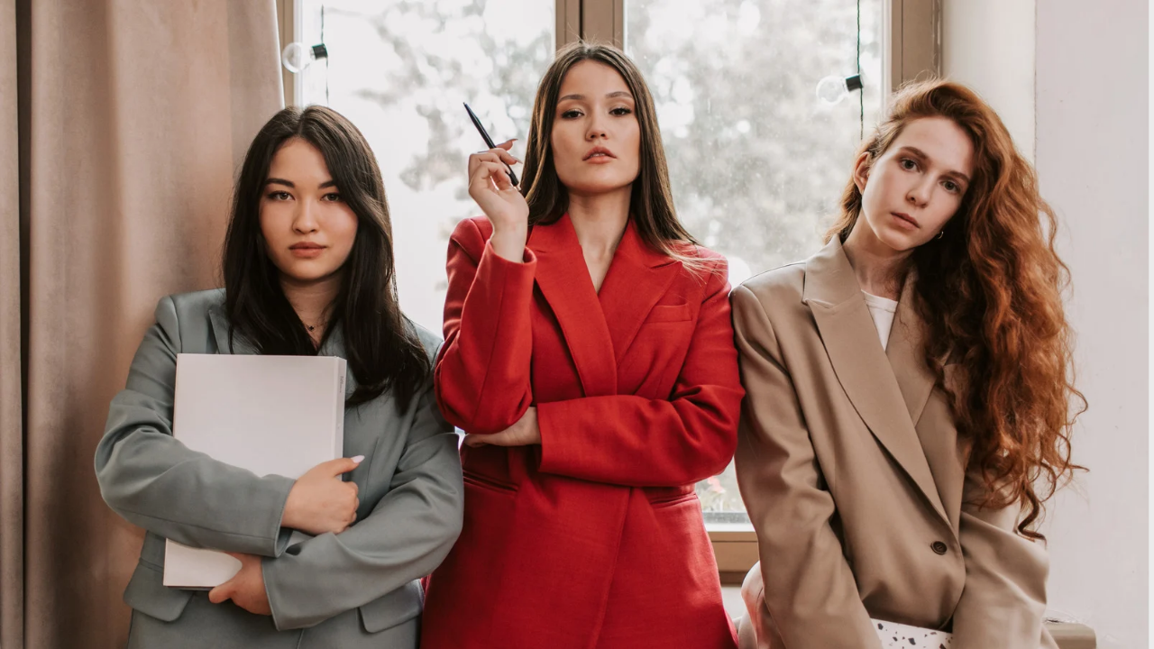 Three stylish white females with grey, red and brown suit/jacket