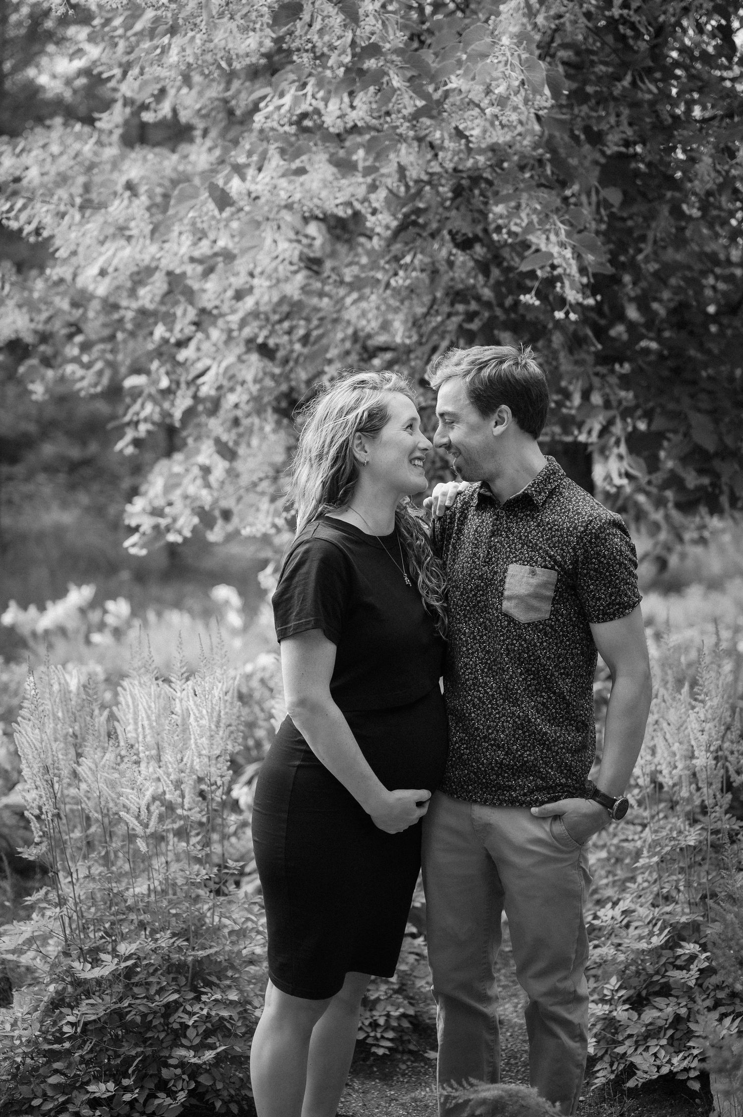 A couple shares an intimate moment outdoors during a maternity photoshoot.