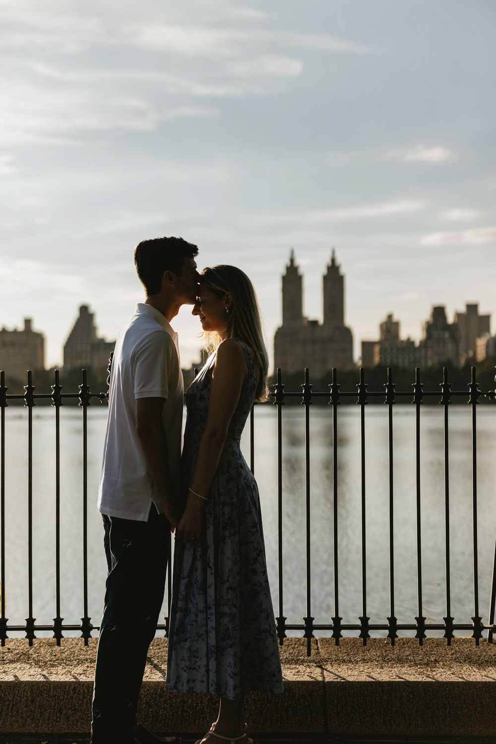 A romantic silhouette of a couple sharing a tender moment against the New York City skyline at dusk.