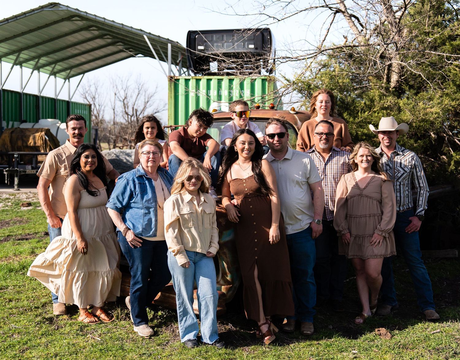 A group of people gather outdoors under a green and white striped awning at a casual outdoor event.