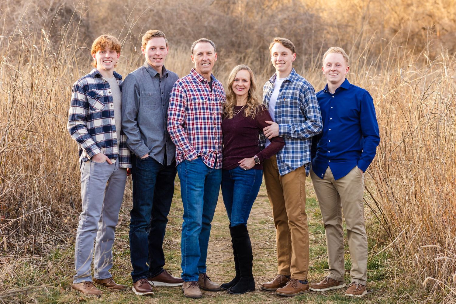 Group photo of six people standing together in casual attire against a backdrop of golden autumn grass.