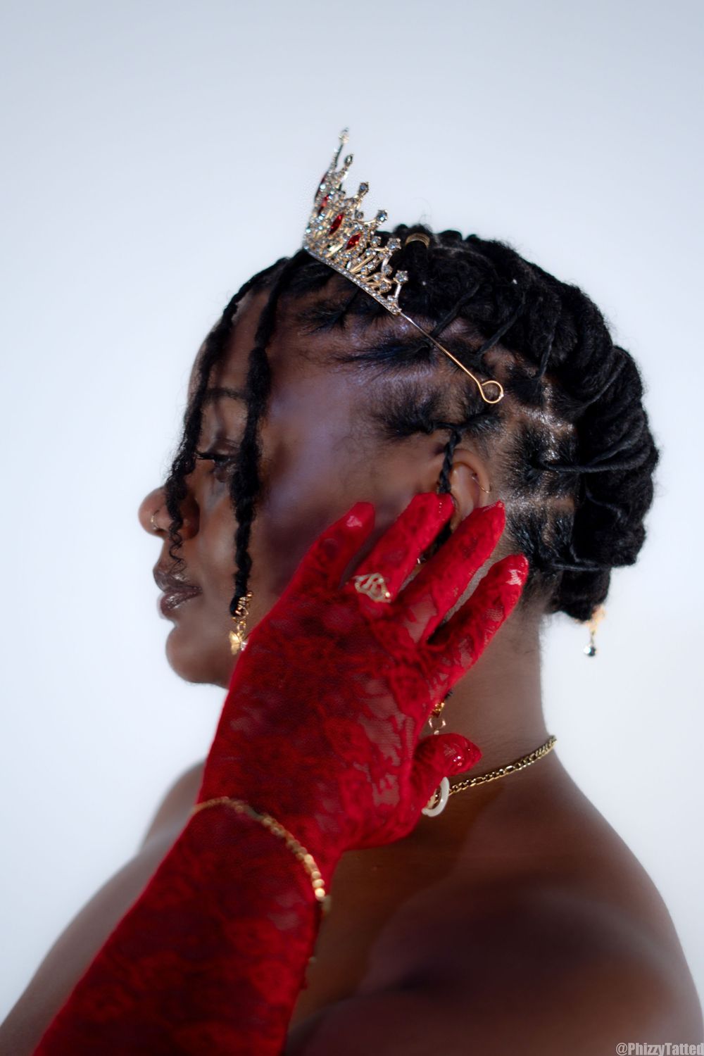 An artistic portrait featuring a crown and red gloves against a white background.