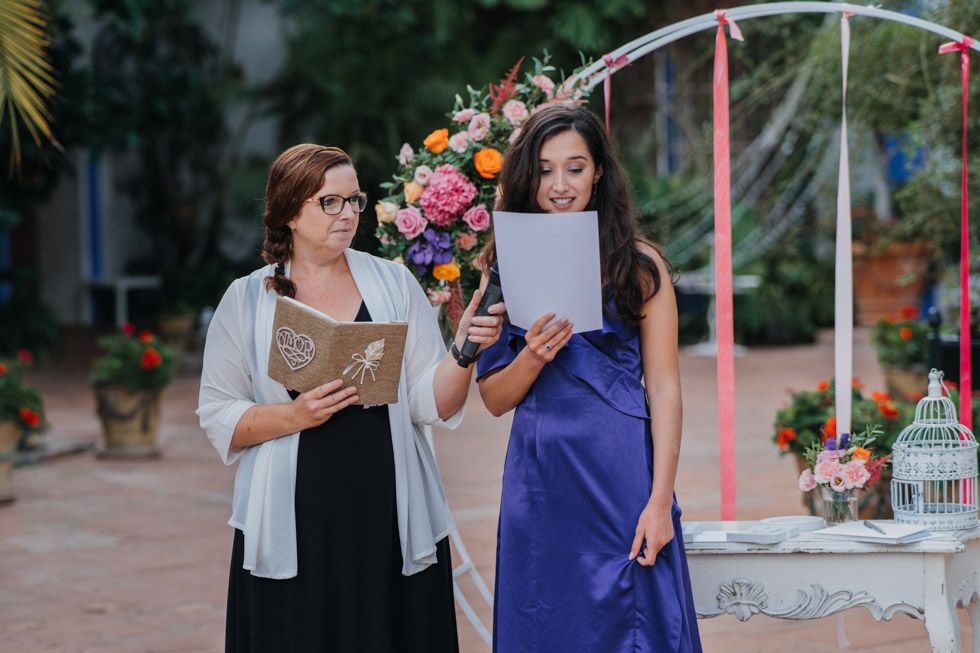 Two women in a garden setting reviewing paperwork with event decor visible in the background.