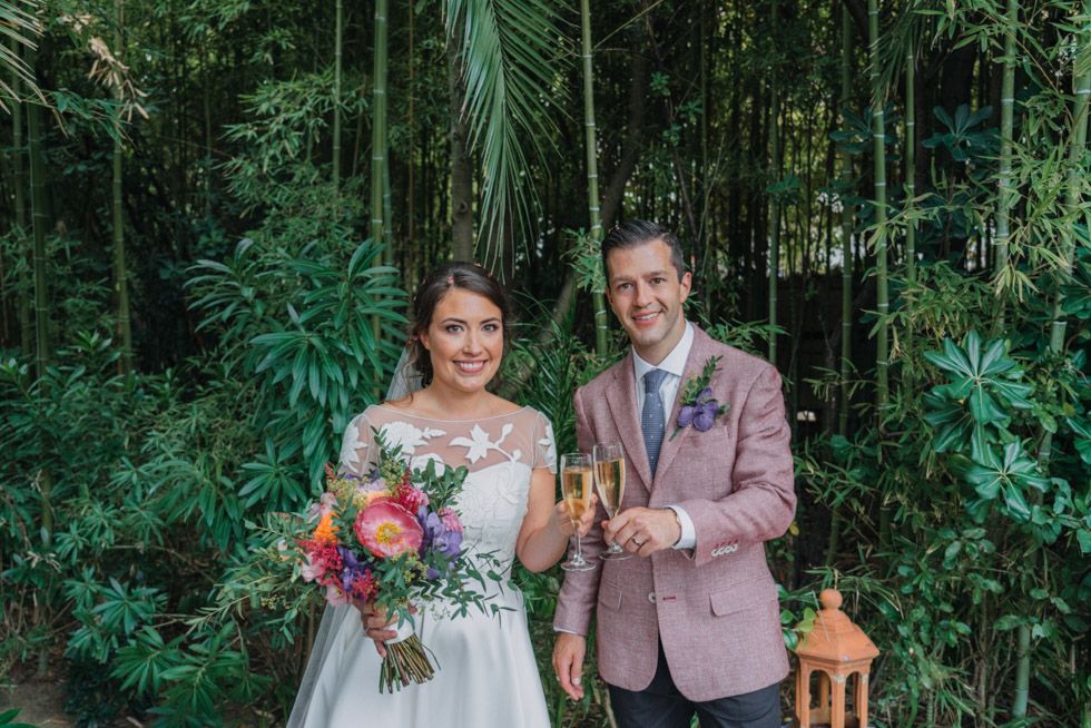 A tropical garden wedding portrait surrounded by lush greenery and bamboo plants.