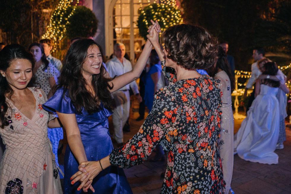 People dancing and celebrating at an evening wedding reception with festive lighting and decorative elements.