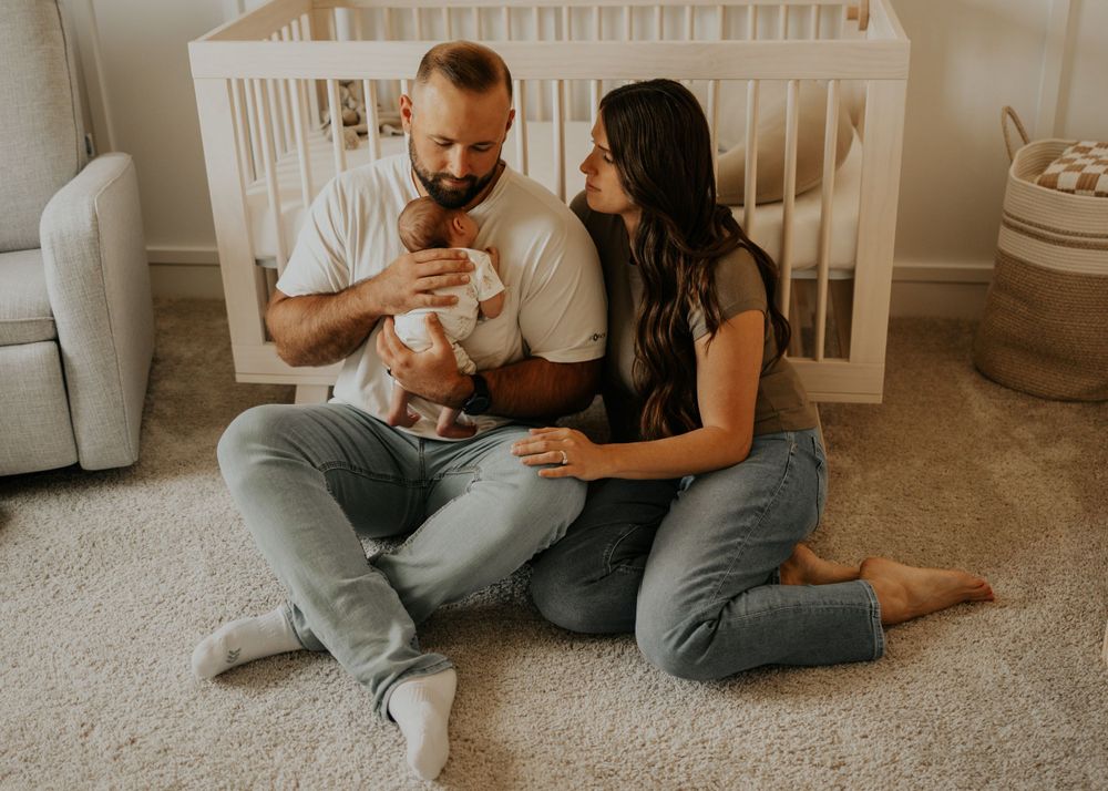 Mom and dad cuddle newborn baby in the nursery at home in Lakeville Minnesota during cozy lifestyle newborn photography session.