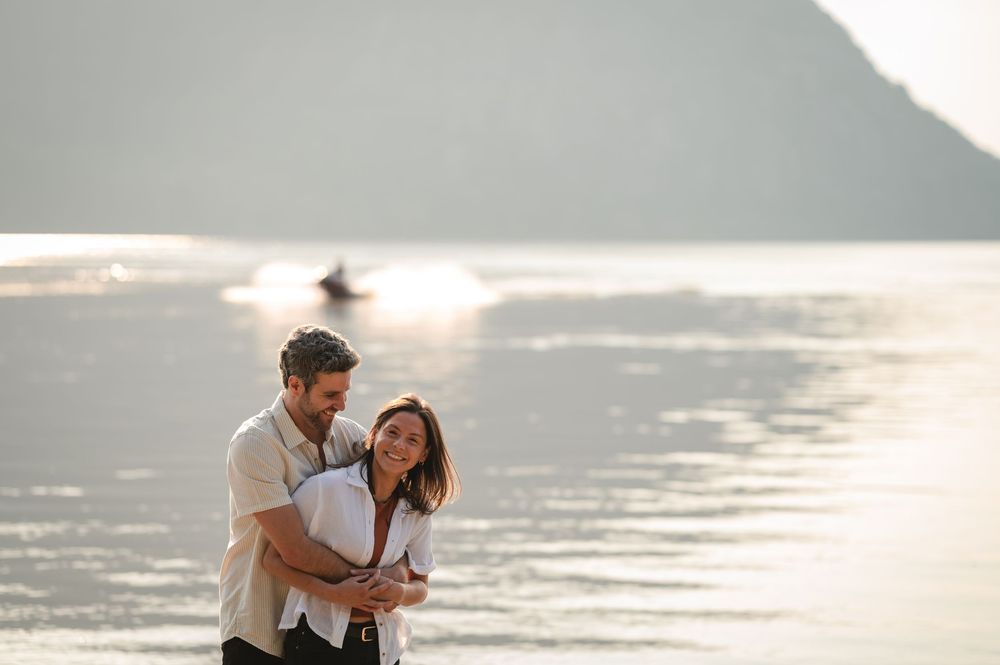 Couple embracing during sunset photoshoot at a scenic lakeside location.