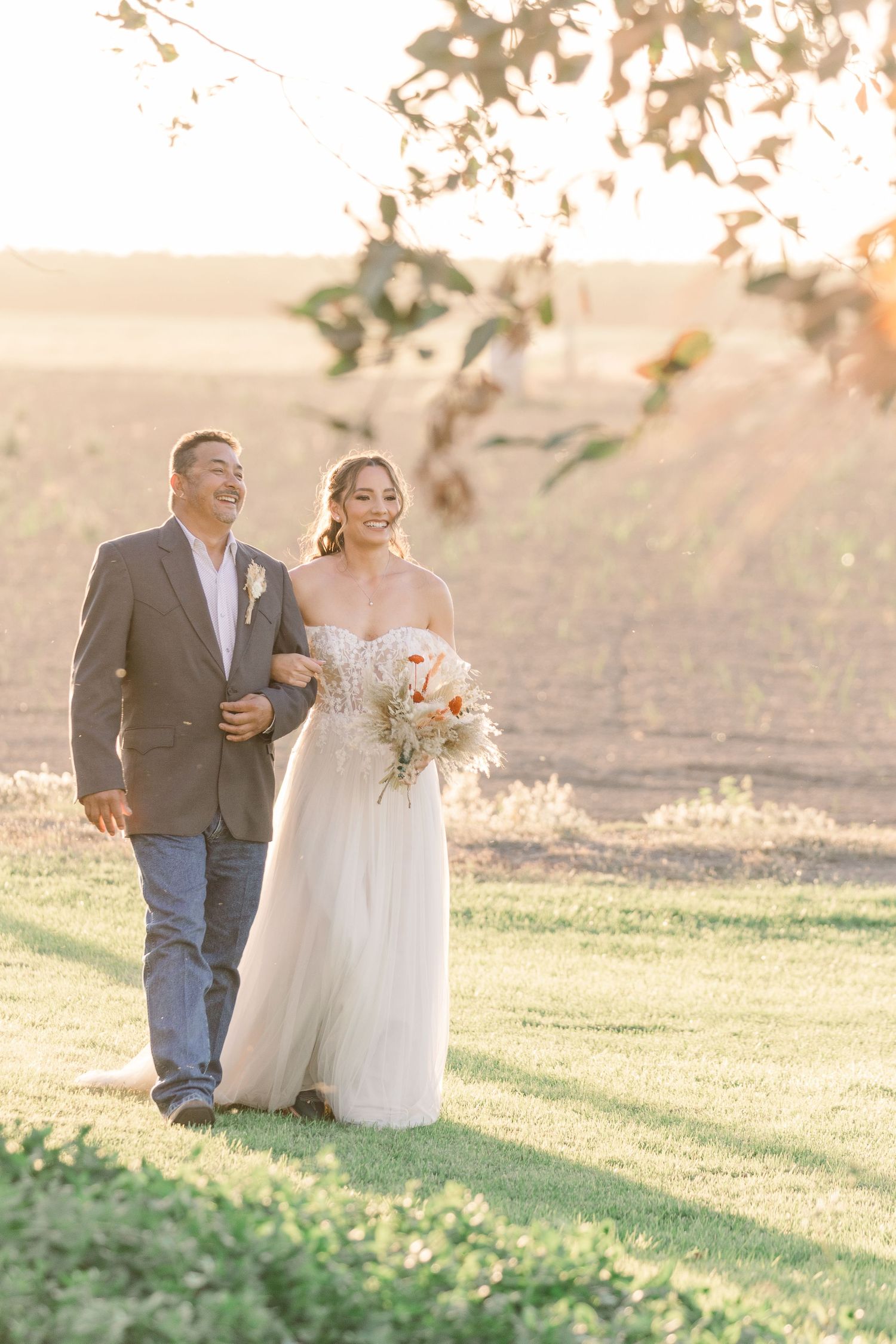 A romantic outdoor wedding photoshoot in a sunlit field with soft natural lighting.