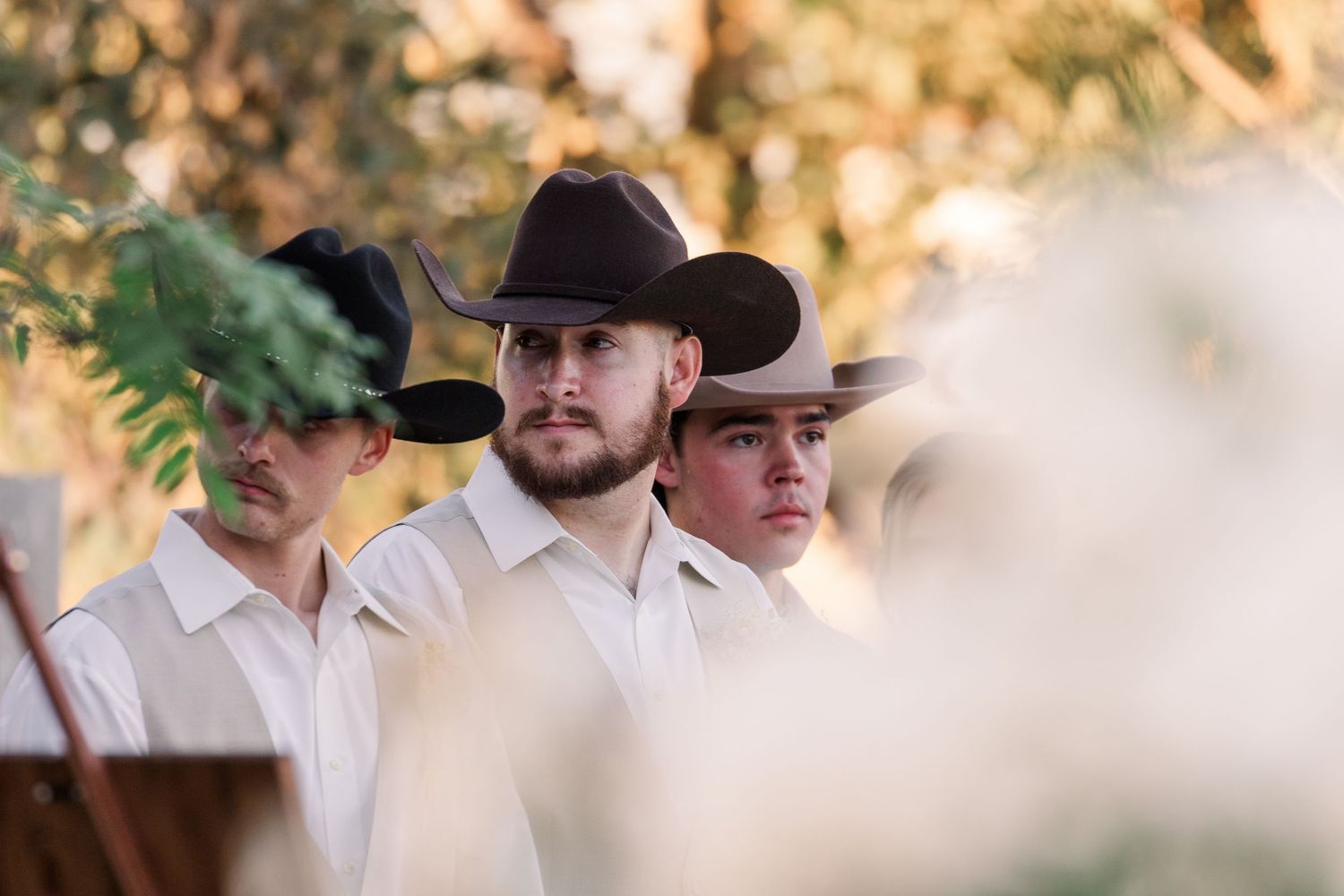 Groomsmen in cowboy hats and western attire at an outdoor wedding.