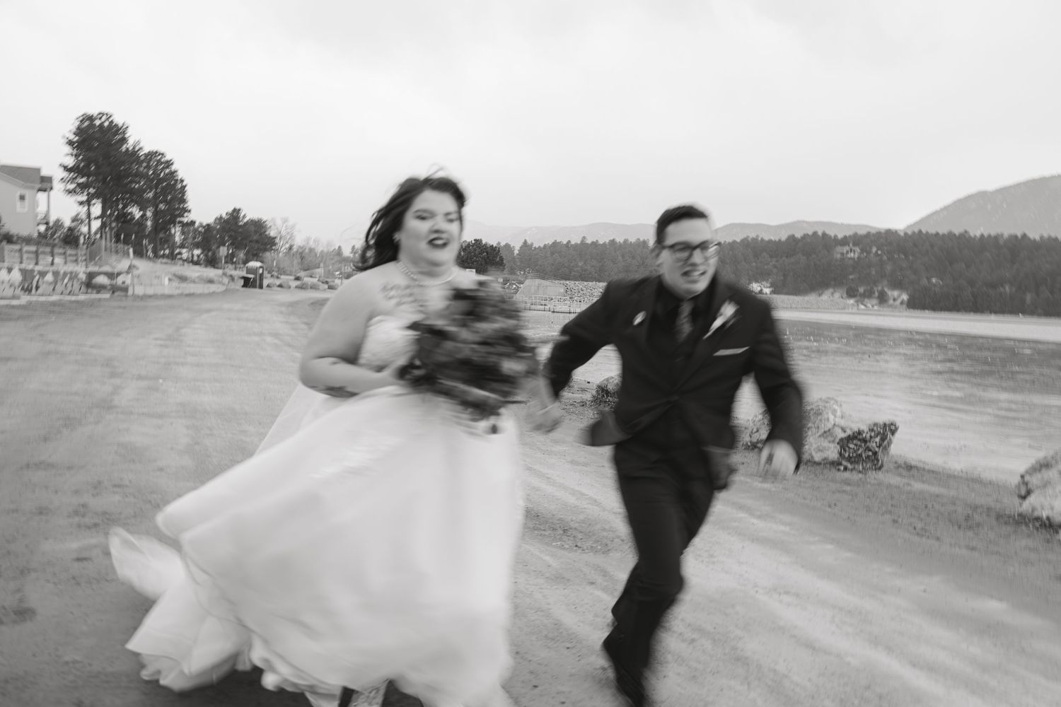Black and white photo of couple dancing joyfully in an outdoor setting.