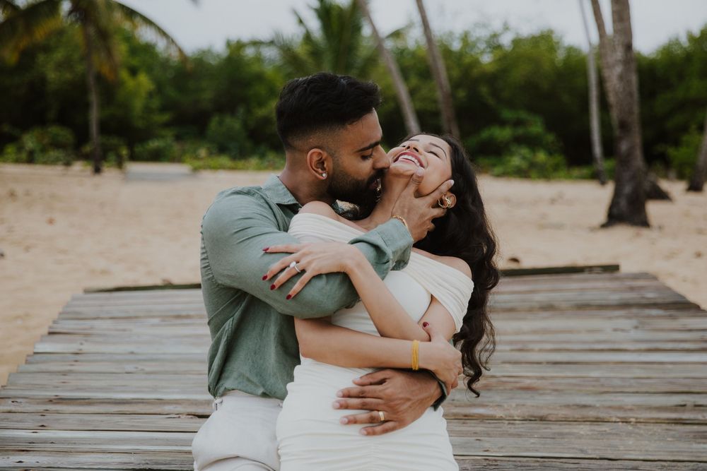 A joyful moment shared between a couple on a tropical wooden boardwalk.