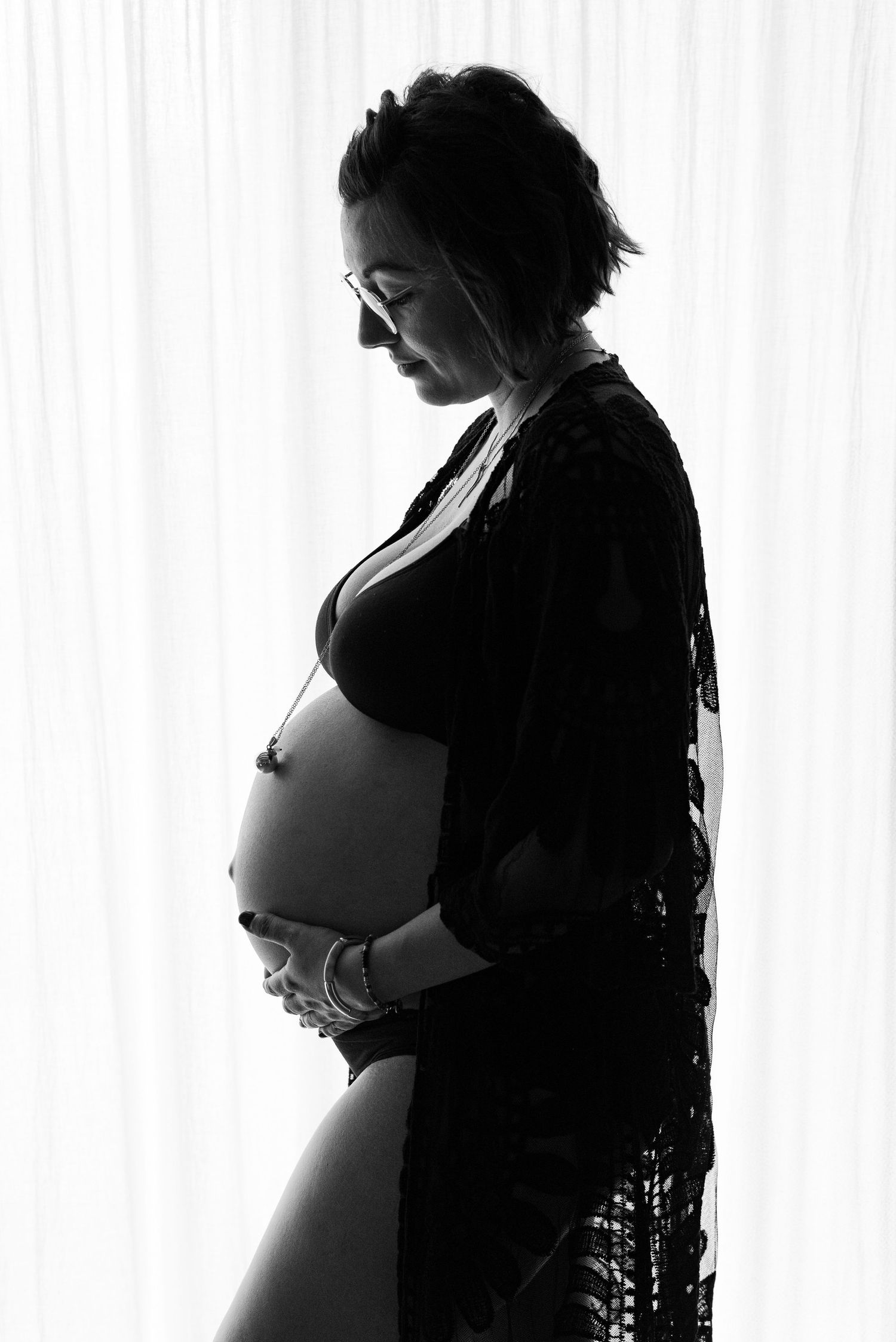 Future maman sereine et heureuse regardant son ventre rond lors d'une mini séance photo au brunch de daronnes dans le beaujolais