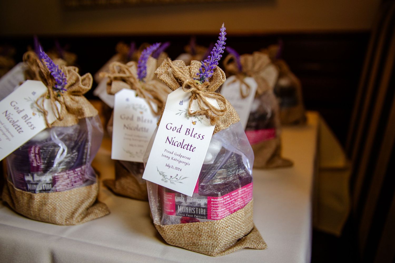 Rustic wedding favors and gift bags arranged on wooden table with handwritten tags and purple accents.