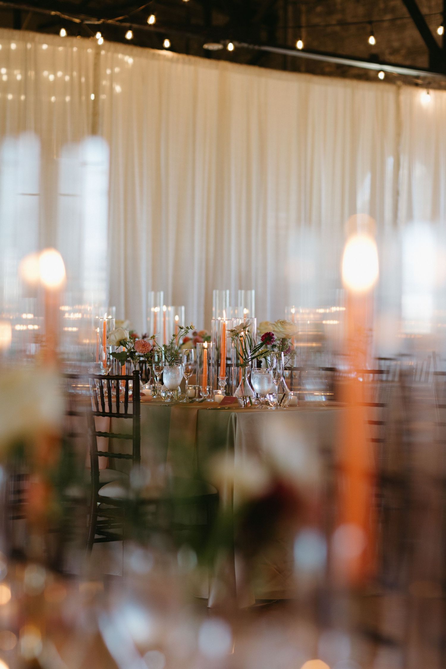 An elegant wedding reception venue with soft draping and warm candlelight creating a romantic atmosphere.