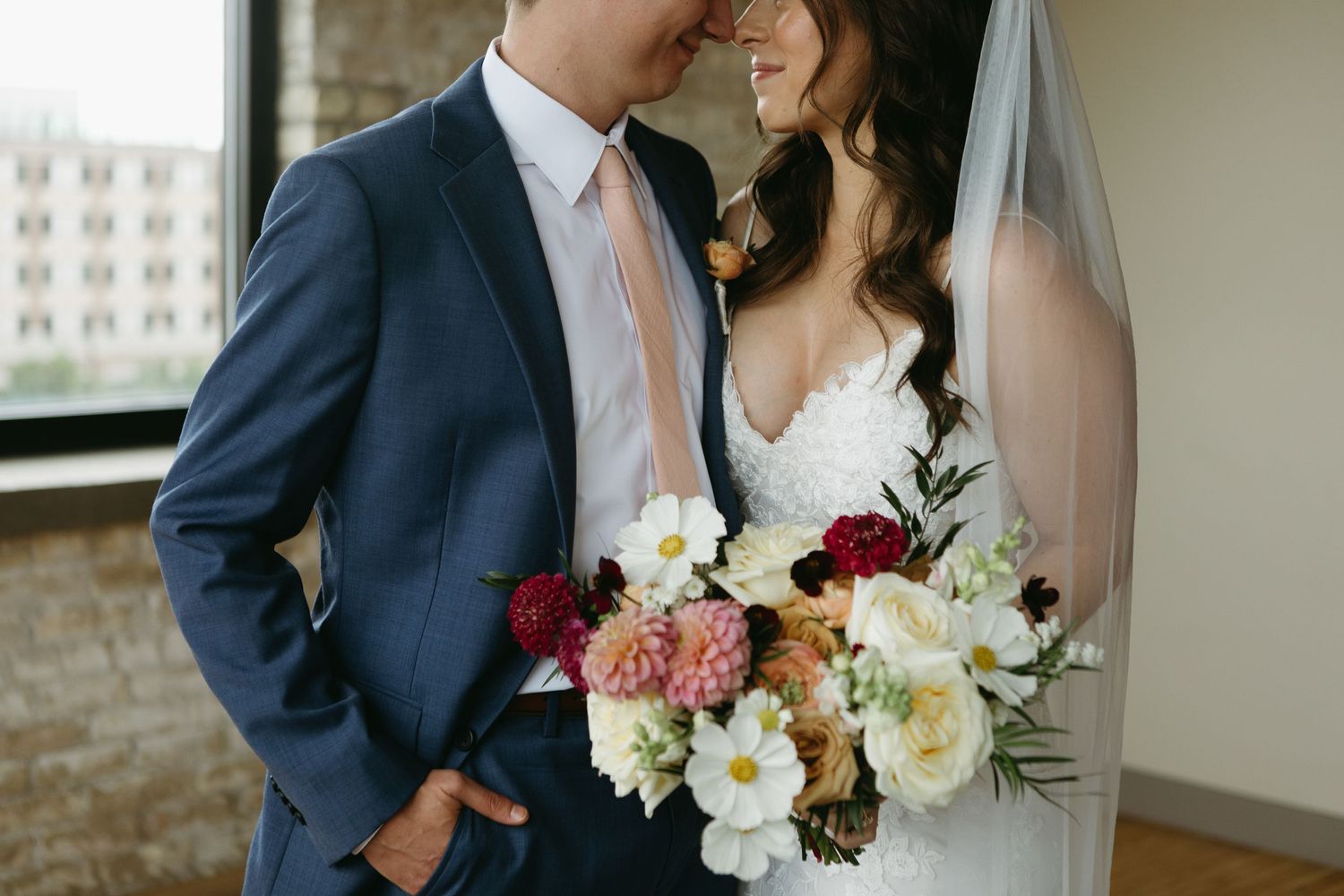 A romantic wedding moment with a bridal bouquet featuring white and burgundy flowers.