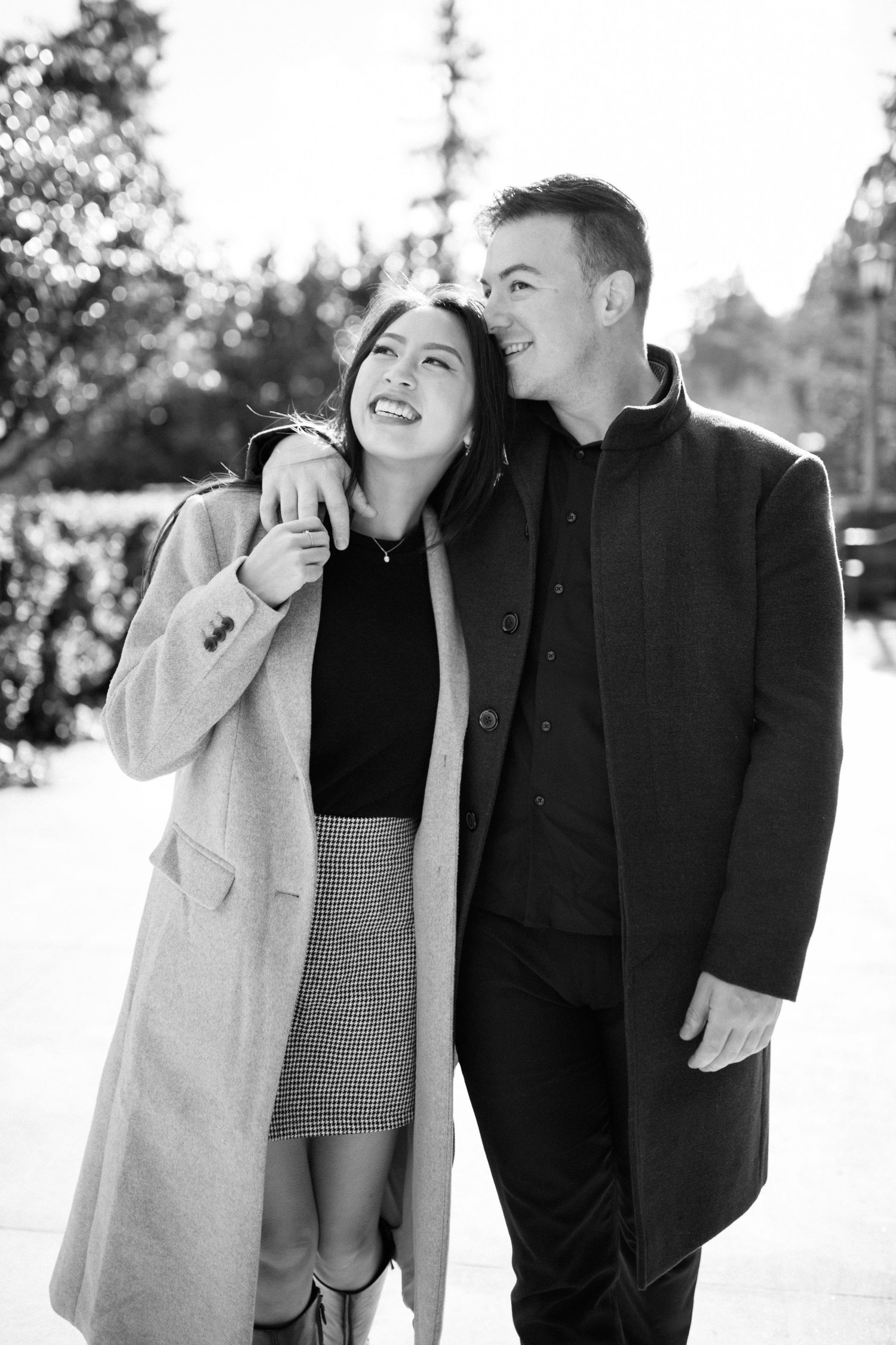 Couple shares a joyful moment together outdoors in black and white photography.