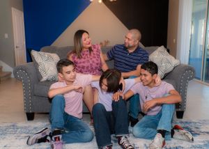 Family of five relaxes and laughs together in their cozy modern living room.