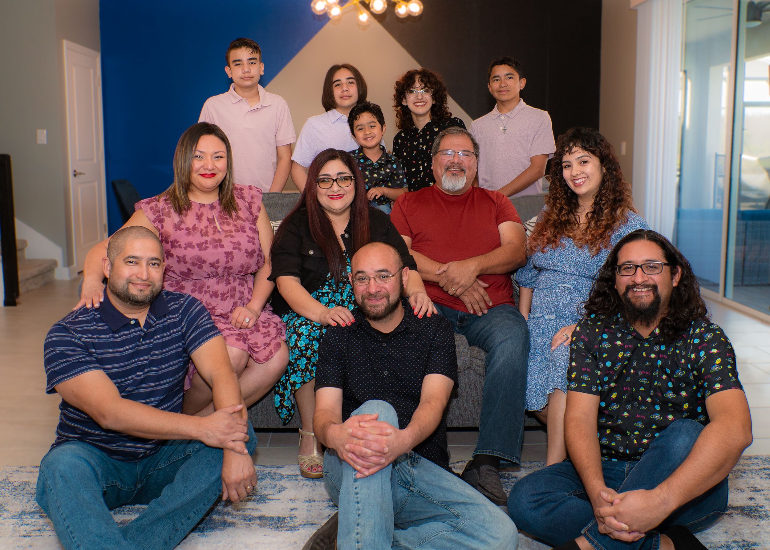 Large multigenerational family smiles together for a group portrait in a modern home.